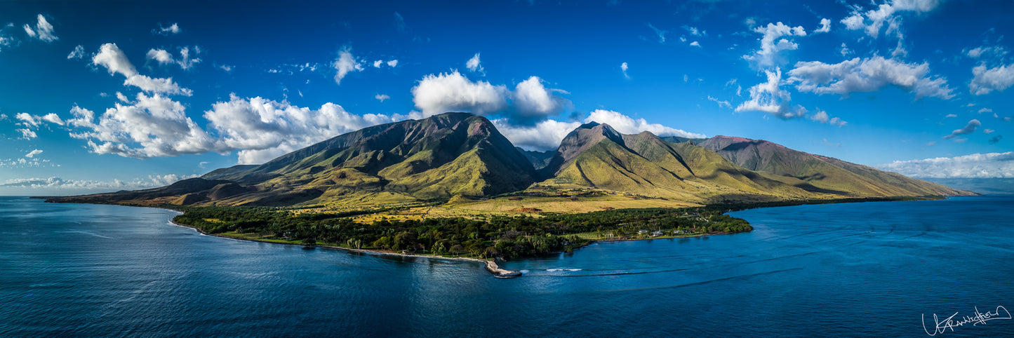 Panoramic view of a mountainous island with blue water and sky.
