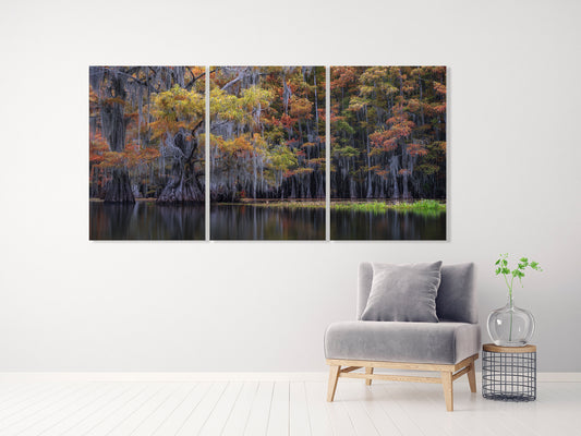 Three-panel wall art of a forest scene above a gray armchair in a room.