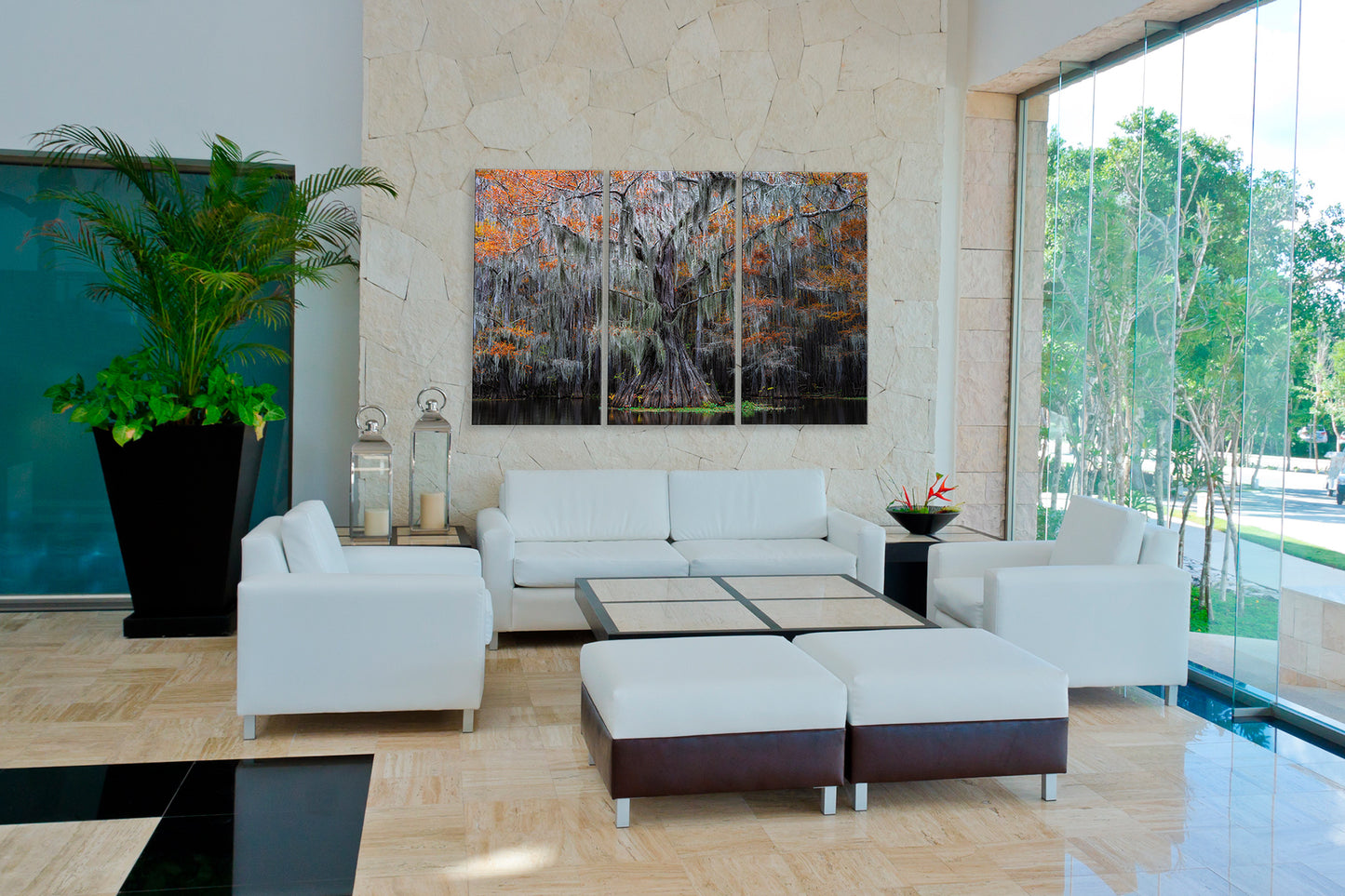 Modern living room with white sofa, ottomans, and abstract art on a stone wall.