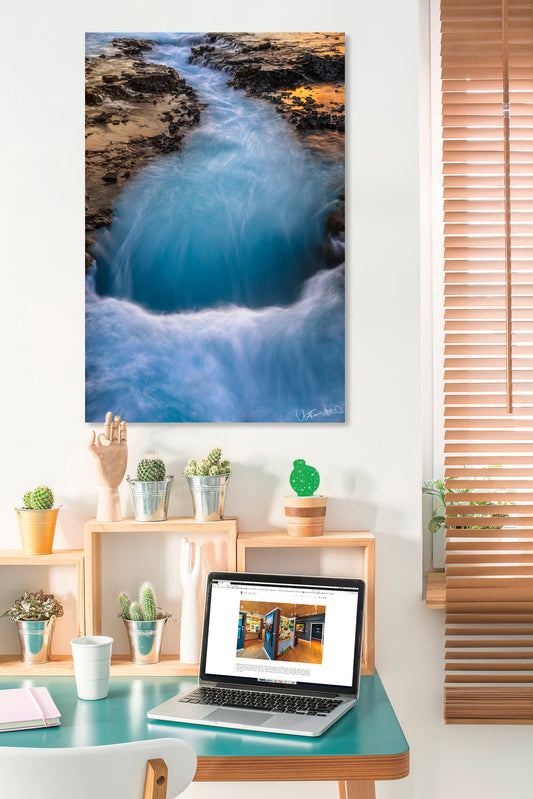 Laptop on a desk with a scenic wall art of a river in a room.