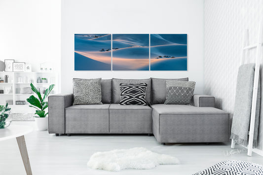 Gray sectional sofa with patterned cushions in a living room setting with multi piece wall art.