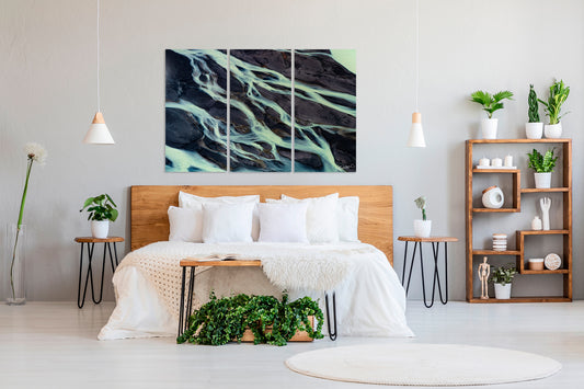 Modern bedroom with a bed, abstract multi panel wall art, and decorative plants.