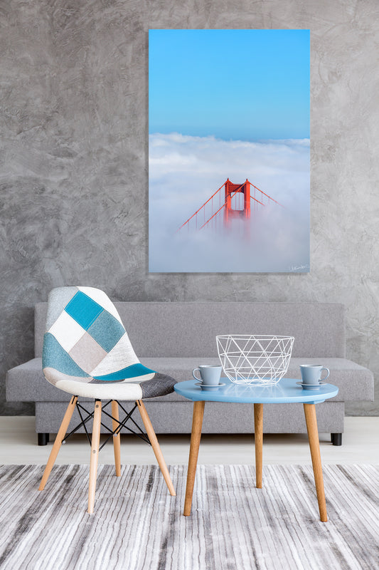 Living room with a gray sofa, patterned chair, and small table with a photograph of the Golden Gate Bridge.