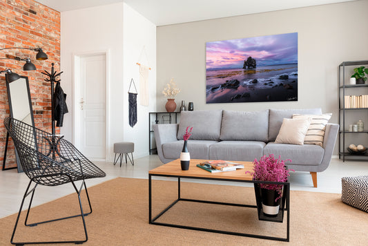 Modern living room with a gray sofa, coffee table, and pink sunset photograph displaying a scenic image.