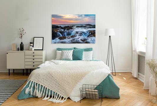 Modern bedroom with a large bed, dresser, and wall art of a sunset over water.