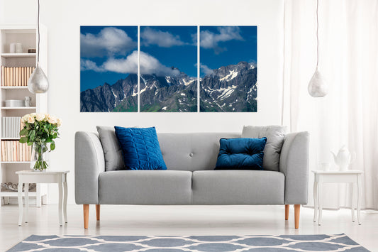 Gray sofa with blue pillows in a living room with a large multi piece wall art.