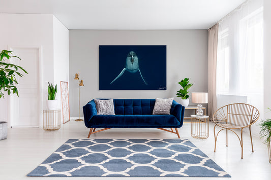 Modern living room with a blue sofa, patterned rug, and a large photograph of a whale.