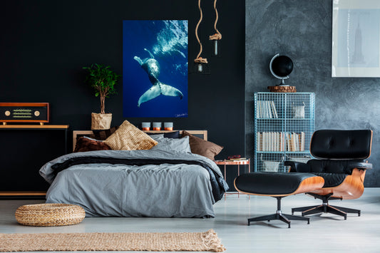Modern bedroom with a bed, ottoman, and wall art of a whale.