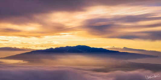 A landscape photograph featuring a beautiful sunset over a mountain range with clouds in hues of orange, pink, and purple.