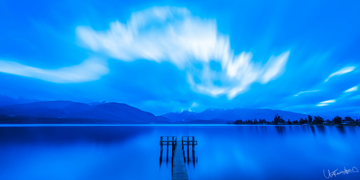 serene lake scene with a dock and mountains under a blue sky