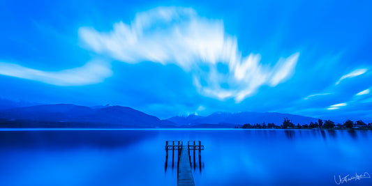  serene lake scene with a dock and mountains under a blue sky