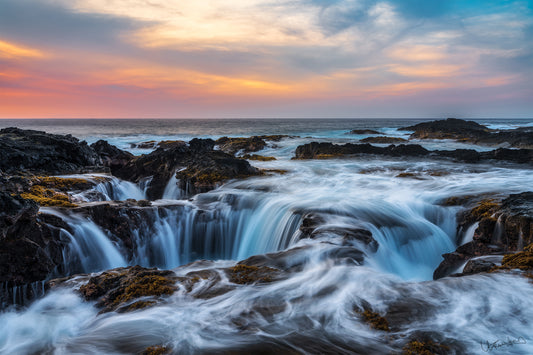 Rocks with waterfalls and a colorful sunset sky
