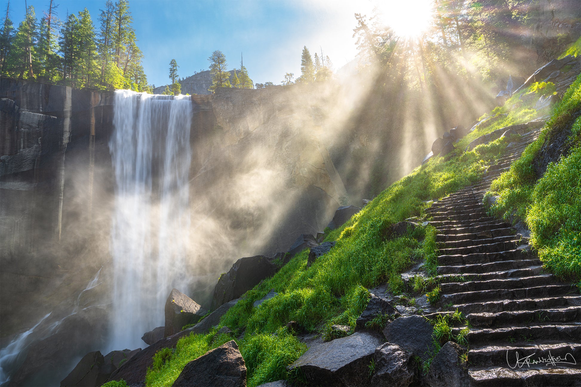 Waterfall with sunlight beams and steps leading up a green hillside