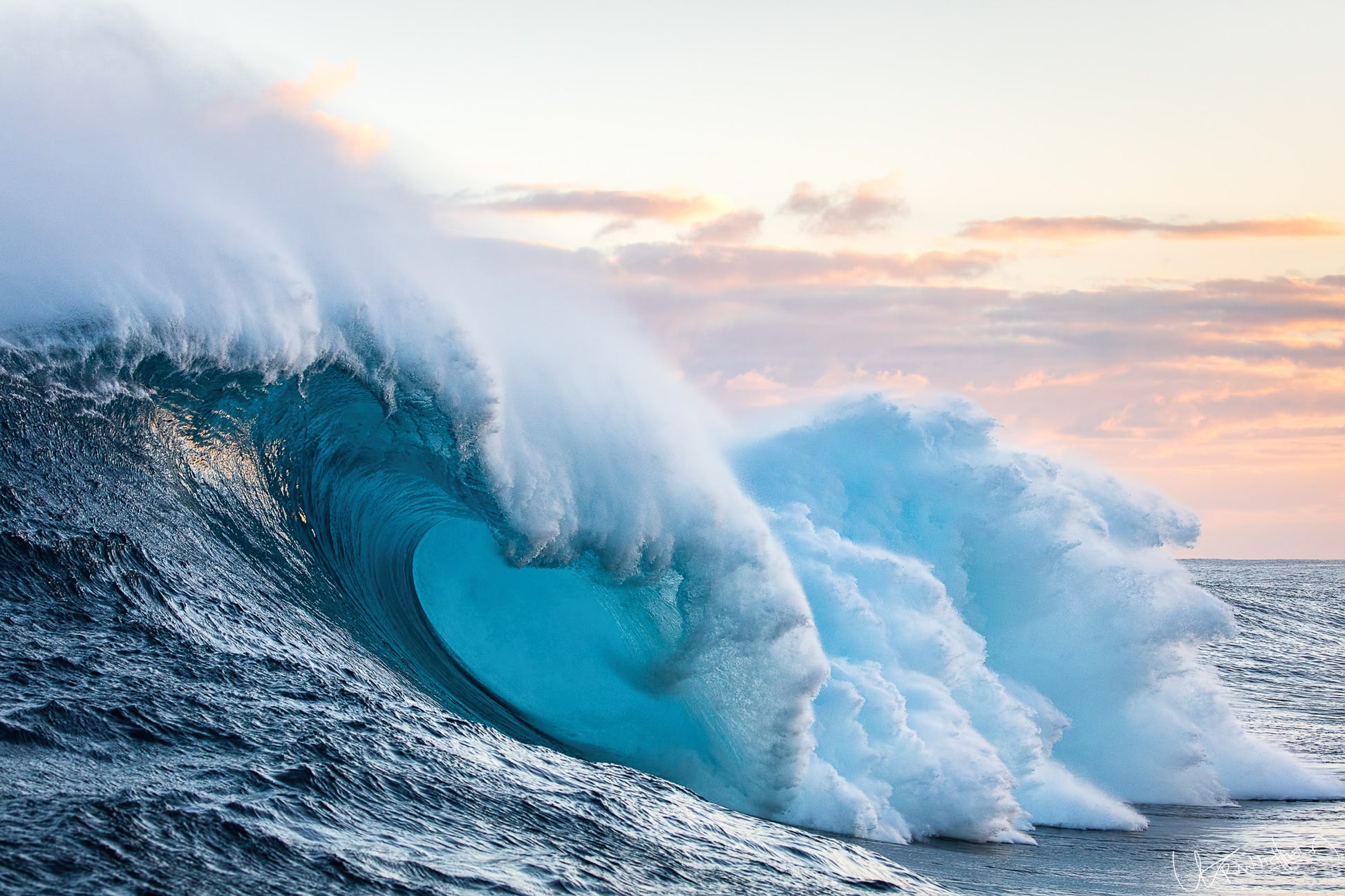 Large ocean waves crashing together with a sunset sky.