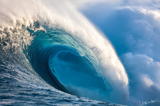 Large ocean wave with white foam against a blue sky