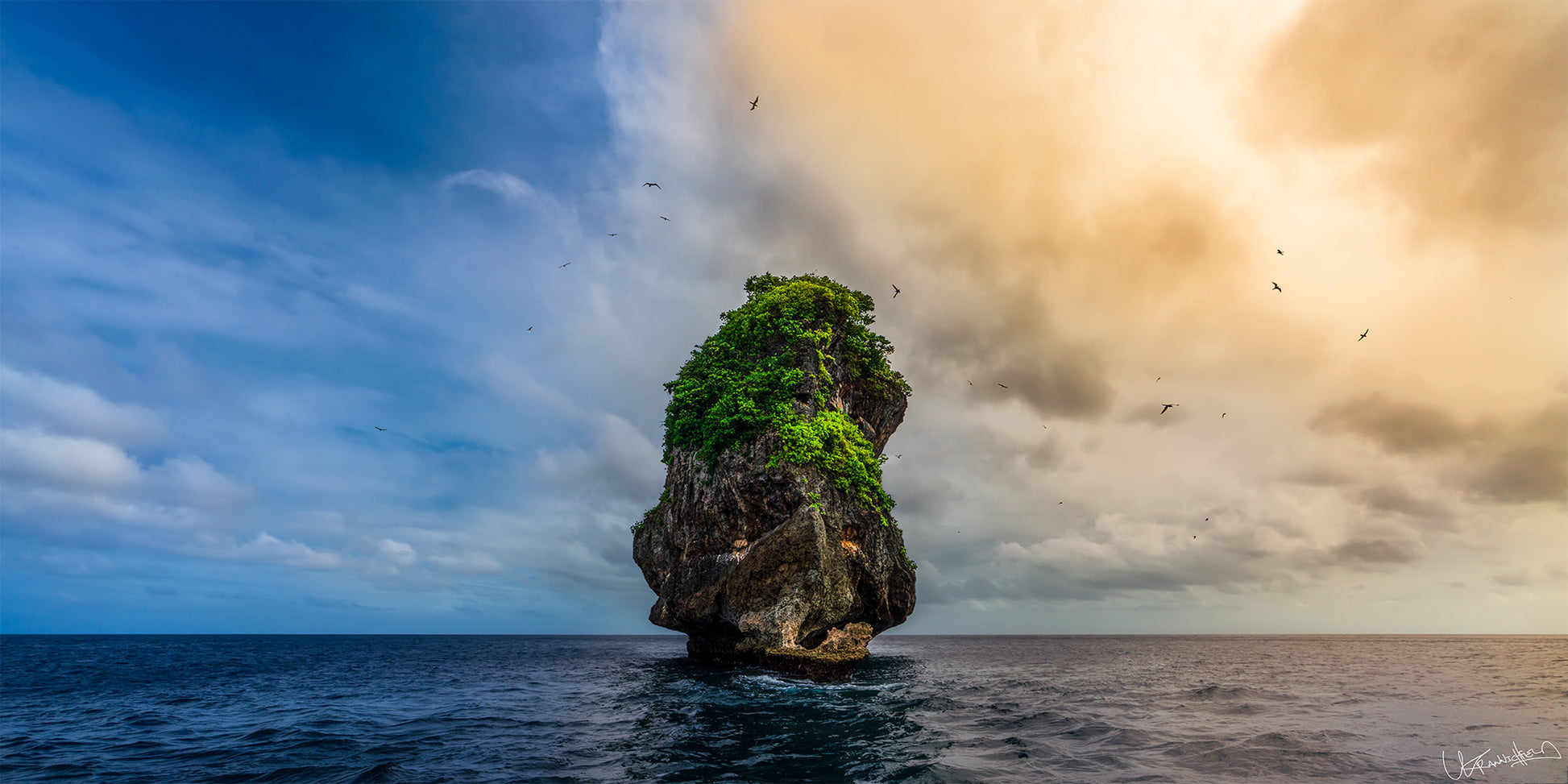 Island rock formation in the middle of the ocean with a dramatic sky.