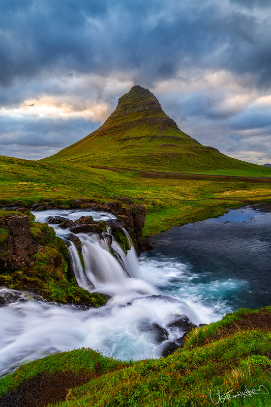 Green mountain with a waterfall and cloudy sky