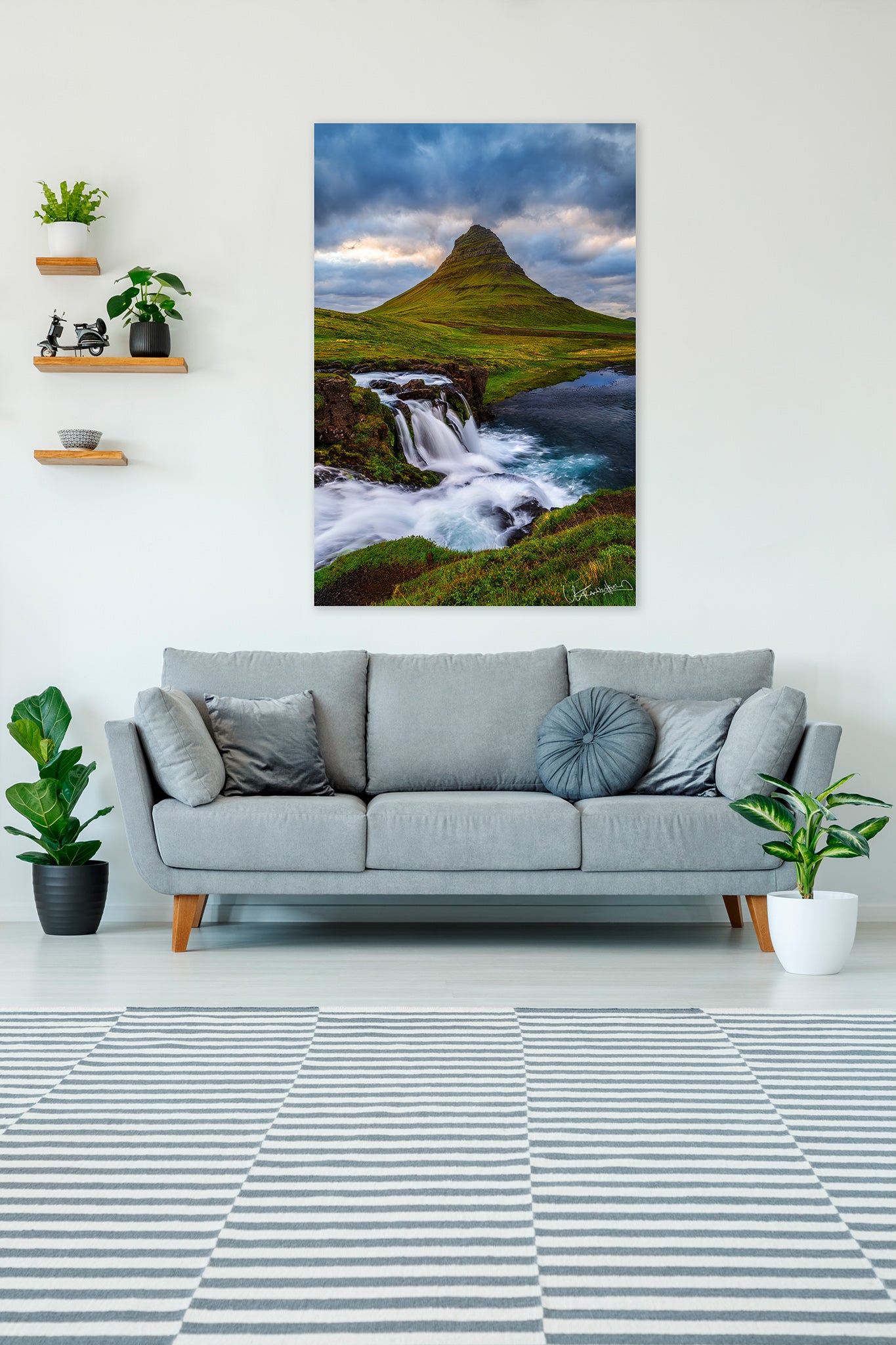 Living room with a gray sofa, striped rug, and a large landscape photo of a mountain and waterfall.