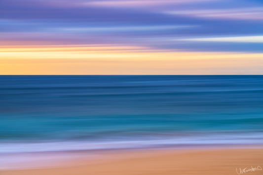 Abstract seascape with blurred water and sand at sunset or sunrise.