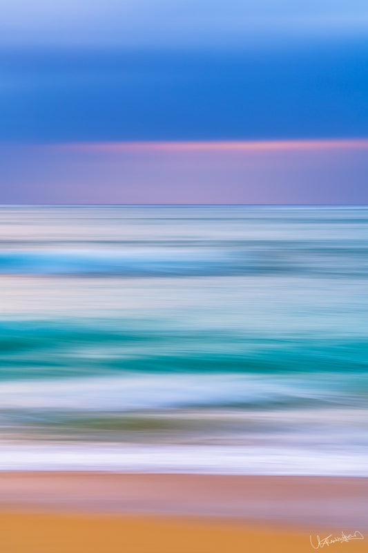 Abstract blurred image of a beach with blue sky and multicolored sand.
