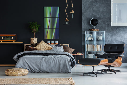 Modern bedroom with dark walls, a bed, and contemporary multi piece artwork.