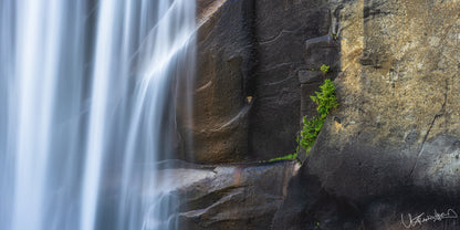 Waterfall cascading down rocky cliff face with greenery