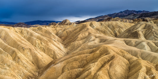 Desert landscape with winding rocky hills under a dark stormy sky